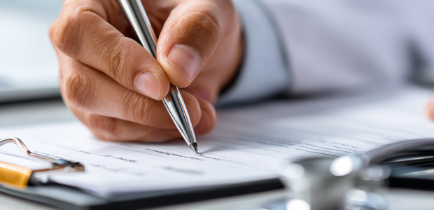 White male medical doctor signing credentialing document