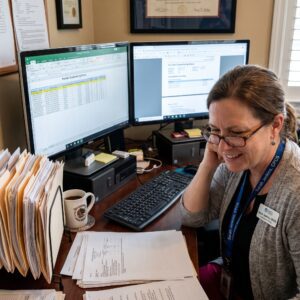 Credentialing Specialist Reviewing Provider Credentialing Status On-screen at Her Desk.